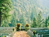 a beautiful wedding ceremony space done with colorful fall leaves and petals, greenery and a fantastic mountain view