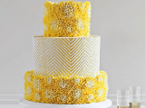 a bright yellow wedding cake with floral textural and chevron tiers is a stylish and bold idea