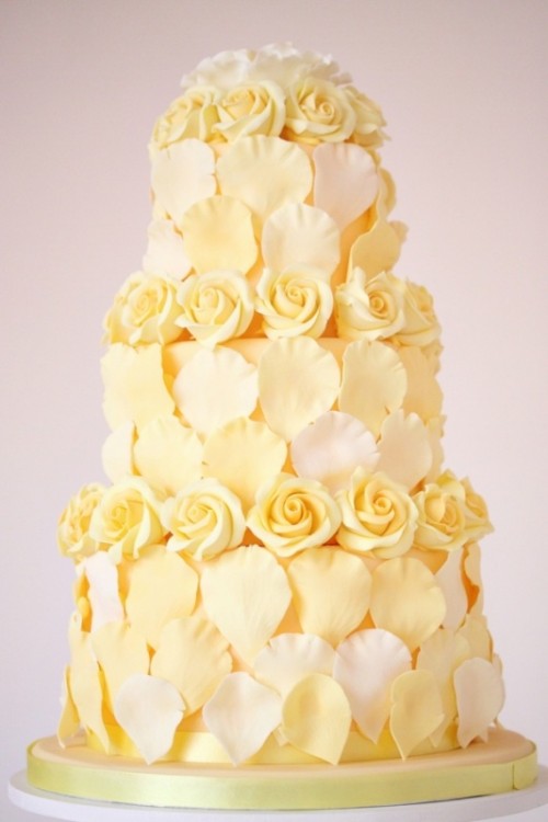 a unique yellow and white wedding cake covered with rose and petals of sugar is wow