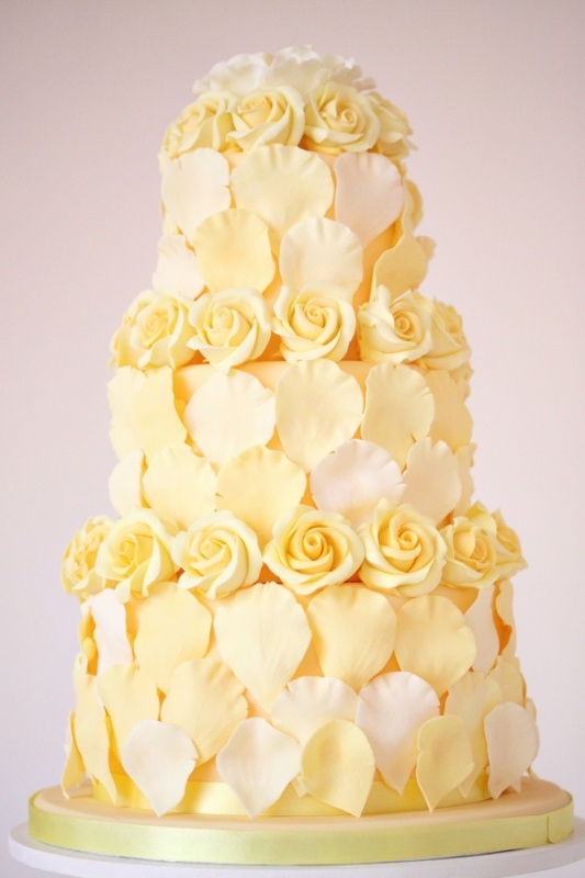 A unique yellow and white wedding cake covered with rose and petals of sugar is wow