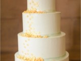 a neutral wedding cake with green ribbons and yellow polka dots is a cool and bold idea for spring or summer