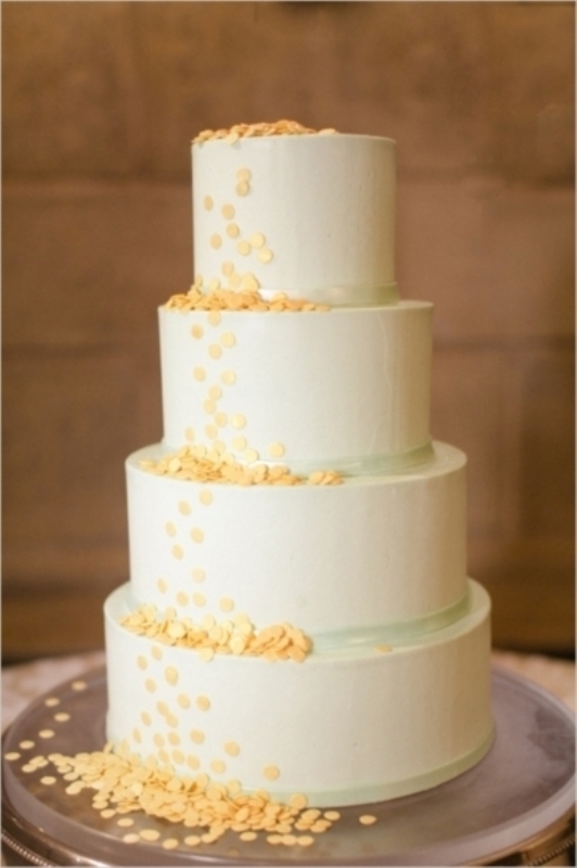 A neutral wedding cake with green ribbons and yellow polka dots is a cool and bold idea for spring or summer