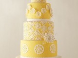 a yellow and white patterned wedding cake with sugar blooms that are dimensional and usual and a sugar bloom on top