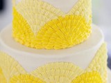 a white wedding cake with pale and bright yellow sugar patterns and some of them on top is a fun and bold idea