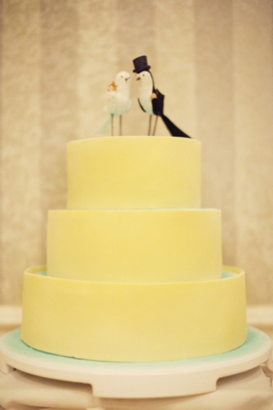 A yellow plain wedding cake with mini birds on top is a stylsh colorful idea to rock