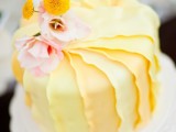 a yellow ruffled tiered wedding cake with pink and yellow blooms is a lovely and refined idea for a vintage wedding