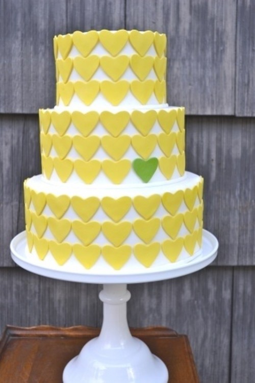 a bold yellow heart wedding cake witha single green heart is a cool and bold idea to rock