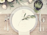 a place setting with an olive branch and a matching green glass for a rustic modern tablescape