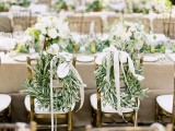 lush olive foliage wreaths with white bows are a nice substitute to usual signage and markers for the couple’s chairs