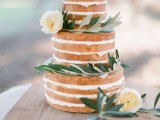 a naked wedding cake with olive greenery and white blooms is a cool idea for spring or summer weddings