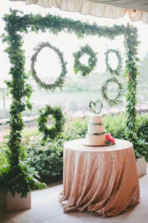 a greenery arch and an arrangement of wreaths of olive foliage and some leaves looks bold and beautiful