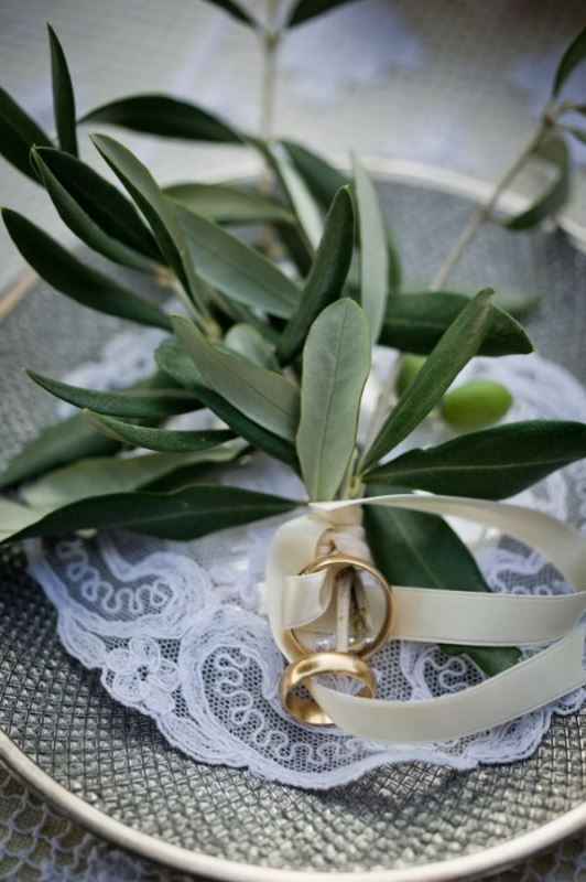 A porcelain plate with a lace doily and some olive branches to hold the rings is a cool idea for a natural wedding