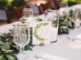 an olive greenery table runner and a matching card to decorate the wedding table in a natural way