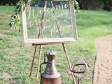 a large wedding sign of an old window and some olive branches on top is a cool idea to decorate the wedding space