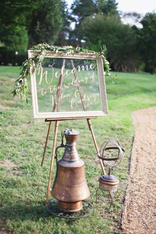 A large wedding sign of an old window and some olive branches on top is a cool idea to decorate the wedding space