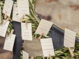 a wedding seating chart with olive greenery, cards and clothespins is a simple and rustic idea for a modern wedding