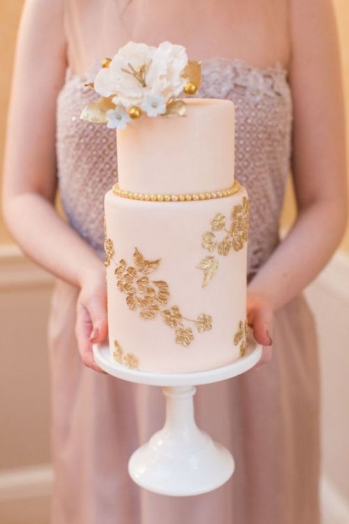 a blush wedding cake with gold floral patterns, gold pearls and sugar blooms on top the cake