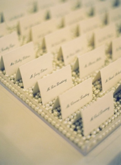 escort cards displayed on a tray with lots of pearls for more elegance and chic