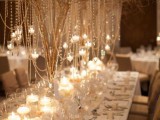 a statement centerpiece of branches with lots of pearls and crystals and candleholders hanging on them