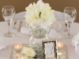 a sheer vase filled with silver pearls, with pearls on the mirror and white blooms plus candles for elegance and chic