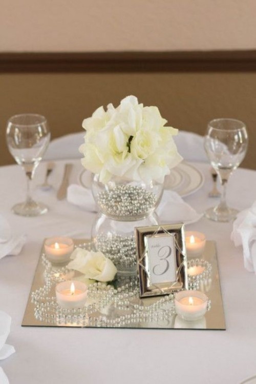 a sheer vase filled with silver pearls, with pearls on the mirror and white blooms plus candles for elegance and chic