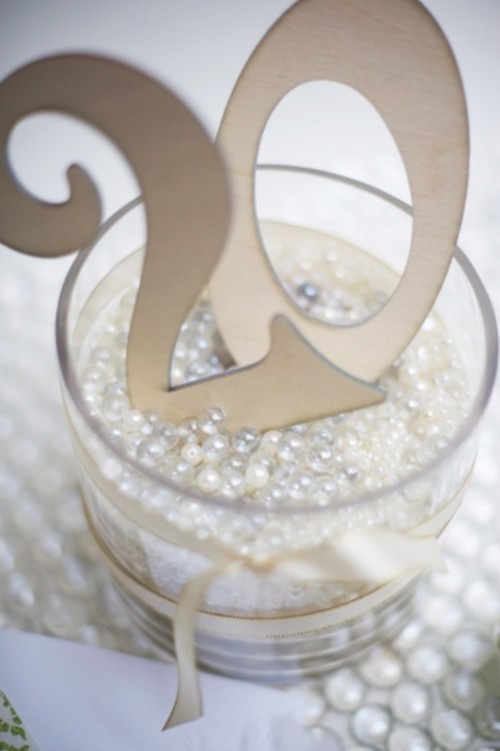 a glass filled with pearls and beads and with table numbers is a cool idea for decorating your table
