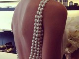 the open back of the wedding dress clad with oversized pearls is a cool glam idea for a bride