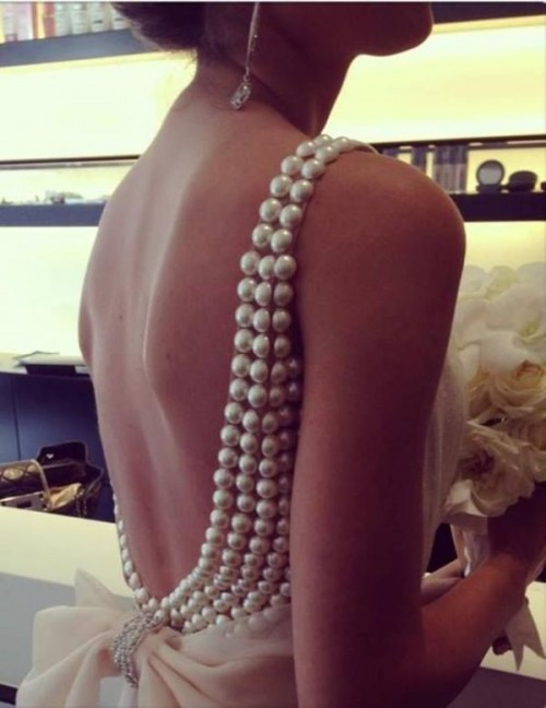 the open back of the wedding dress clad with oversized pearls is a cool glam idea for a bride