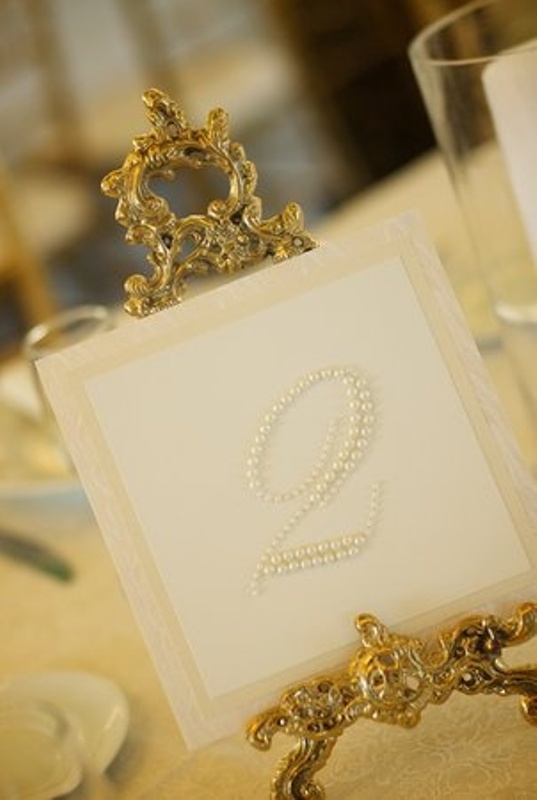 A refined wedding table number with pearls and decorated with gold is chic, bold and stylish
