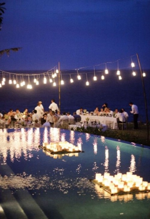 pendant lamps and candles floating on the trays in the pool will make your wedding reception space feel like a destination one