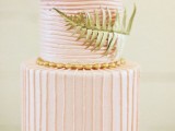 a striped light pink wedding cake with horizontal and vertical stripes, with a large fern leaf is a lovely idea for a tropical wedding