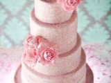a light pink confetti wedding cake with pink sugar blooms on top, with a white ribbon and a bow is a lovely idea for a cute glam wedding