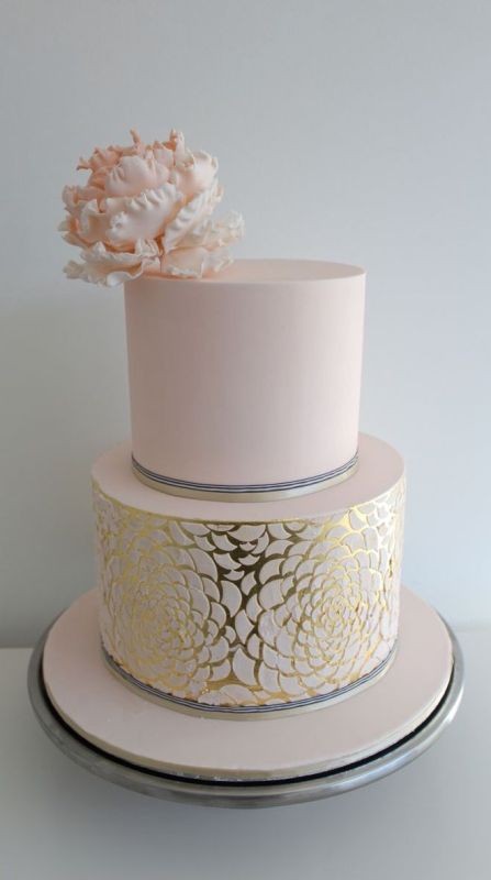 a sophisticated and glam pink and gold leaf wedding cake with a large pink flower on top is perfect for a refined wedding