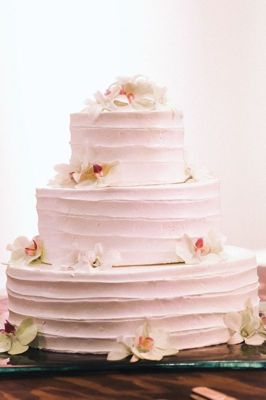 A very simple pink striped buttercream wedding cake topped with orchids is a cool idea for a tropical wedding, and the delicate color contrasts the blooms