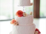 a pink textural buttercream wedding cake topped with orange, white and blush blooms and with little bird toppers is very creative and fun