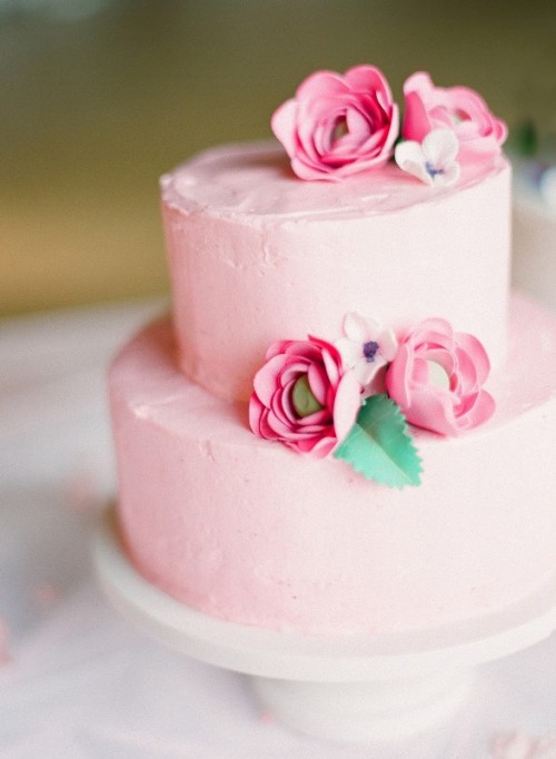 a light pink textural buttercream wedding cake with pink sugar flowers and a leaf is a colorful and cheerful idea for a summer wedding