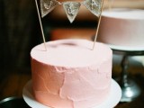 a cute pink textural buttercream wedding cake with a burlap banner topper and some crochet hearts is a very cool solution for a modern wedding