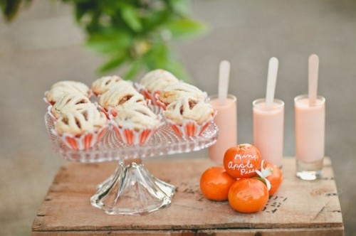 a sweets table with souffle, tangerins and frosted cupcakes covered with orange liners is a great idea for a summer wedding