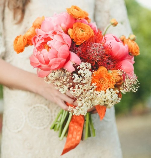 a super bright wedding bouquet of pink peonies, orange ranunculus, white blooms and orange ribbon is amazing for summer