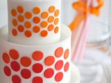 a white wedding cake decorated with colorful polka dots and a couple of flags on top is a bold and colorful idea for a modern wedding