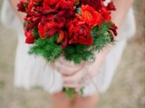a bold red flower bouquet with fir branches is a stunning piece to complete your bridal look