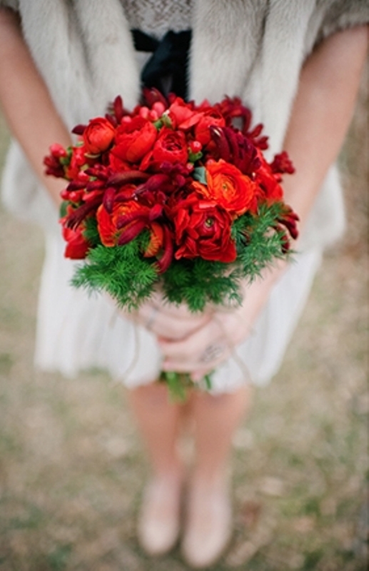 A bold red flower bouquet with fir branches is a stunning piece to complete your bridal look