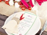 a winter or Christmas wedding tablescape dotted with red and grene touches, with potted herbs and menus and napkins