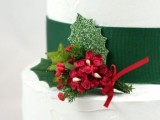 a white wedding cake with a green ribbon, green leaves and berries is a traditional idea for a winter wedding