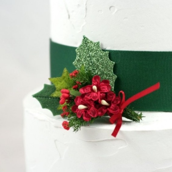 A white wedding cake with a green ribbon, green leaves and berries is a traditional idea for a winter wedding