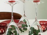 glasses with greenery, berries inside and red candles on top for decorating a winter or Christmas wedding