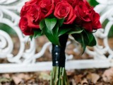red roses, a black wrap with buttons is a chic and stylish winter wedding bouquet that never goes out of style