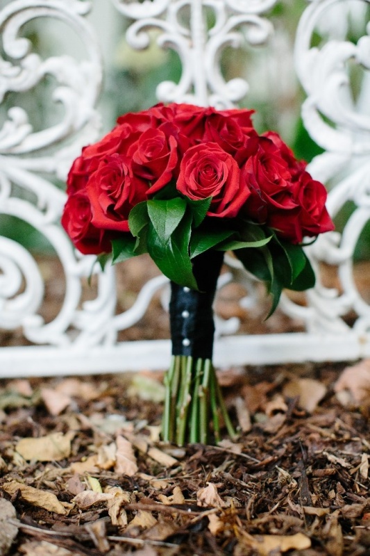 Red roses, a black wrap with buttons is a chic and stylish winter wedding bouquet that never goes out of style