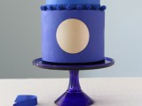 a blue wedding cake with a light blue and bold blue tier, with sugar decor and a gold circle is amazing for a bright wedding