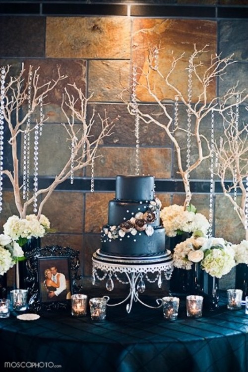 a midnight blue wedding cake with white and dark gold sugar blooms, pearls and beads is a refined and chic idea that will easily fit many weddings